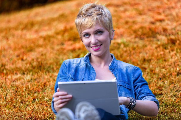 Krótkowłosa kobieta bada swój tablet, fuzja technologii i przyrody otacza ją - Zdjęcie, obraz