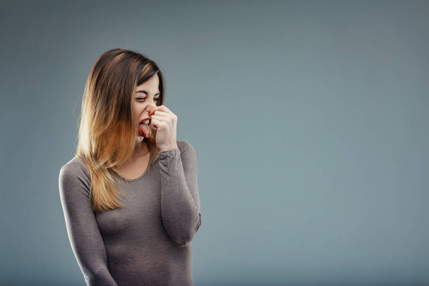 twarz kobiety otarcia w niesmak, reagując na nieprzyjemny zapach jak dym lub zanieczyszczenia - Zdjęcie, obraz