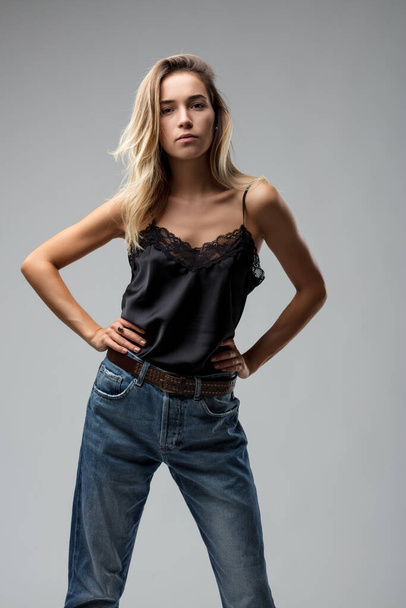 Руки на бедрах, ее взгляд такой же бескомпромиссный, как модное заявление она делает с ее кружева и джинсы - Фото, изображение