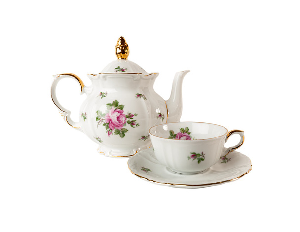 Tetera de porcelana, taza de té y platillo con adorno de rosa floral en estilo clásico aislado sobre blanco
 - Foto, Imagen