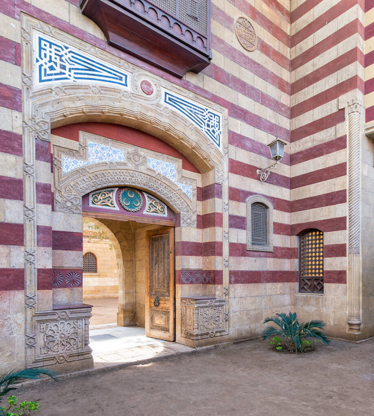 Úchvatný červenobílý pruhovaný klenutý vchod vede do budovy ve stylu Mamluka, představující složité architektonické detaily - Fotografie, Obrázek