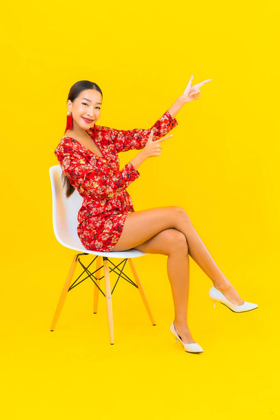 Портрет красива молода азіатка зі смартфоном і сидить на стільці
 - Фото, зображення