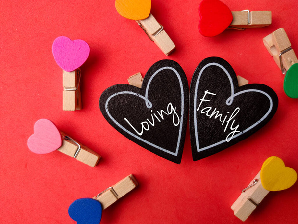 Top view clips en bois colorés et planche d'amour en bois avec texte Loving Family sur un fond rouge. - Photo, image