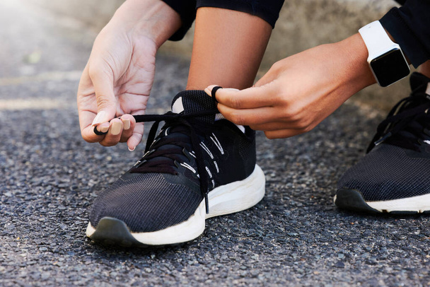 Fitness, hands and tie shoes on road to start workout, training or exercise legs outdoor. Closeup, runner and tying lace on sneakers at street in preparation for sport, health and wellness of woman. - Photo, Image