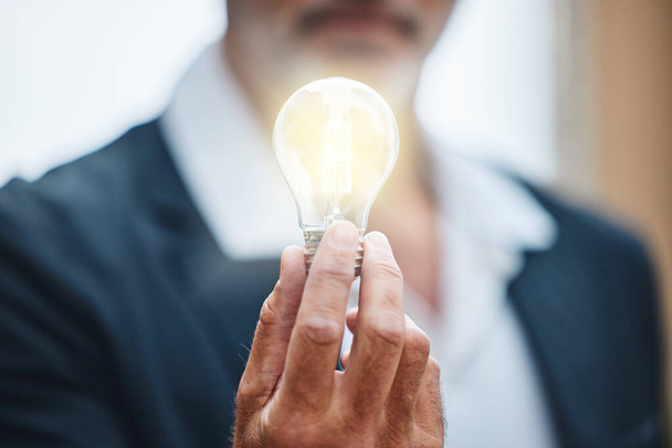 Businessman, bright and hand with light bulb for idea, innovation and creative knowledge for vision for sustainability. Hand, solution and renewable energy, electricity and power saving or eco plan. - Photo, Image