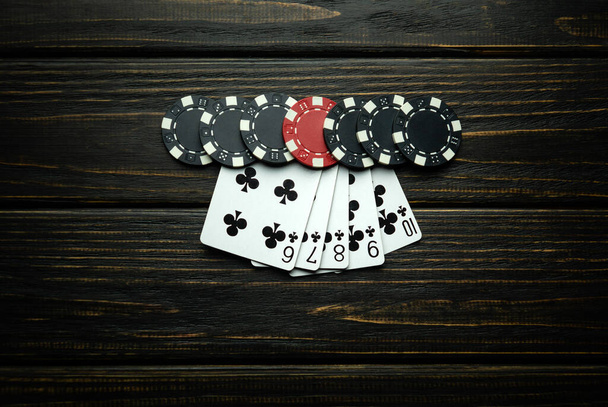 人気のあるエキサイティングなポーカーゲームで,勝利のストレートフラッシュコンビネーション. ポーカークラブのダークヴィンテージテーブルのチップ付きカード. - 写真・画像
