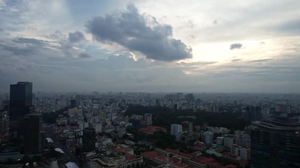 Ein Stadtbild von oben bei Sonnenuntergang, mit Wolken am Himmel, die eine farbenfrohe Atmosphäre schaffen. Hochhäuser und Gebäude säumen den Horizont und spiegeln sich im Wasser unter Ho-Chi-Minh-Stadt Vietnam - Filmmaterial, Video