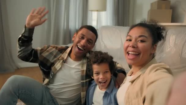 Boldog vidám afro-amerikai család vicces boldog szülők anya apa kisfiú fiú gyerek mosoly beszélgetés videó hívás rekord élő blog mobiltelefon kamera az új otthon költözés napján ünneplik áthelyezés - Felvétel, videó