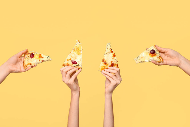 Vele handen houden pizza plakjes op gele achtergrond - Foto, afbeelding