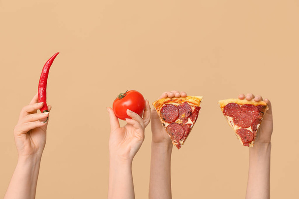 Many hands holding pizza slices, tomato and chili on beige background - Photo, Image