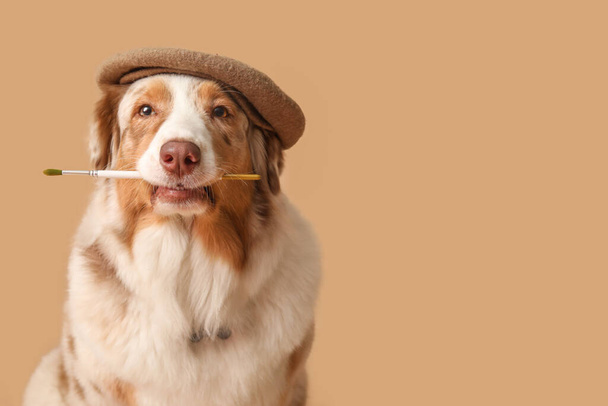 Cane carino in berretto e con pennello su sfondo beige - Foto, immagini