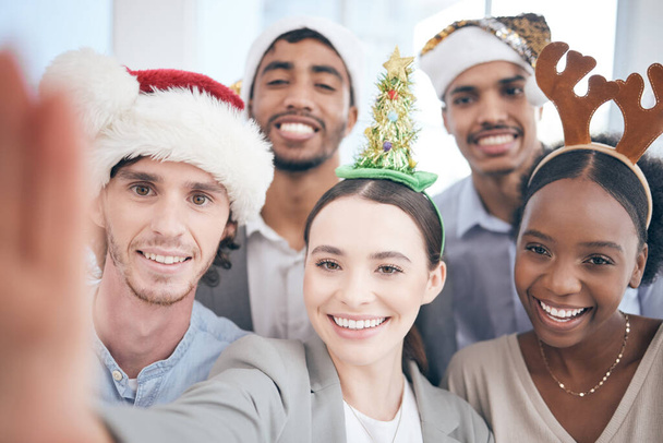 Biznesmeni, selfie i święto Bożego Narodzenia za współpracę, wakacje i uroczyste przyjęcie w miejscu pracy. Różnorodność, praca zespołowa i zacieśnianie więzi biznesowych w biurze na wakacje, portrety i pamięć pracowników. - Zdjęcie, obraz