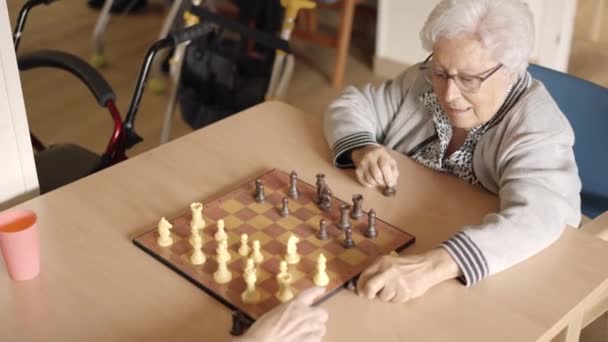 Hidasliikkeinen video kaksi vanhaa naista pelaa shakkia geriatrisessa - Materiaali, video