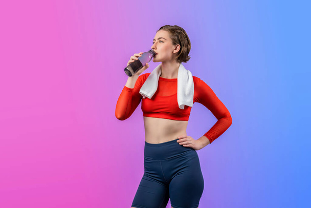 Vücut uzunluğunun tamamı atletik ve sportif genç bir kadını havluyla ve içme suyuyla izole edilmiş arka planda egzersiz yaparken çekilir. Sağlıklı aktif ve vücut bakımı yaşam tarzı. - Fotoğraf, Görsel