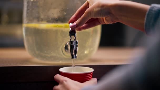 primer plano de las manos cerca del mostrador de la barra vertiendo limonada en un vaso de papel rojo - Metraje, vídeo
