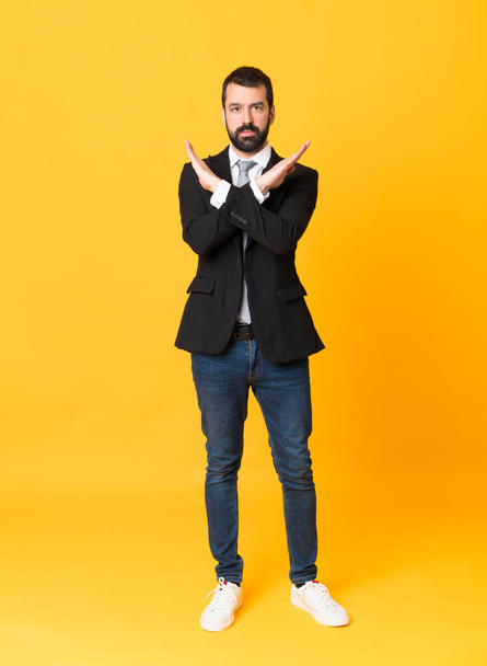 Full-length shot of business man over isolated yellow background making NO gesture - Fotografie, Obrázek