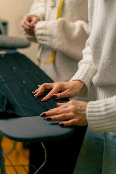 de cerca en un taller de costura costurera alfileres de un alfiler corrugado en un tejido negro - Foto, Imagen