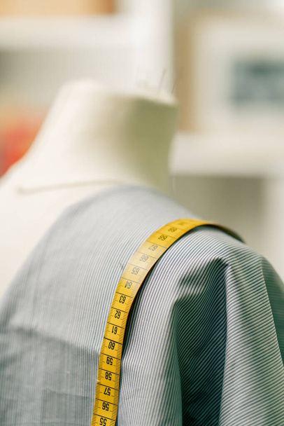 primer plano de un maniquí en un taller de costura con un paño azul cubierto y un centímetro - Foto, Imagen