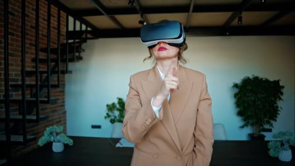 Donna gesticolare mentre utilizza un auricolare di realtà virtuale in un ufficio - Filmati, video
