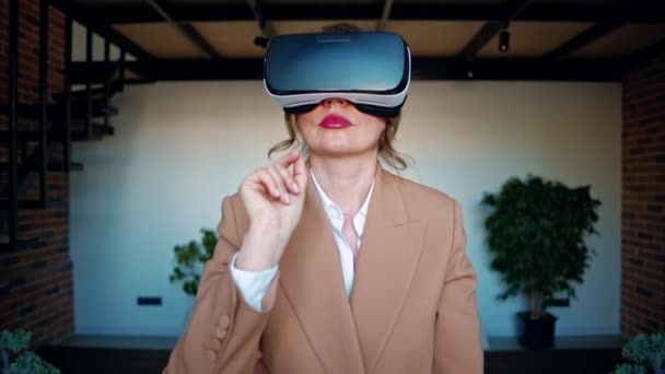 Mujer haciendo gestos mientras usa un auricular de realidad virtual en una oficina - Metraje, vídeo