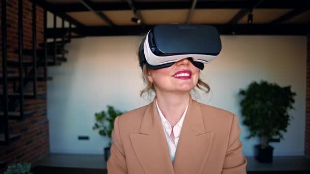 Kobieta uśmiechnięta podczas korzystania z zestawu słuchawkowego Virtual Reality w biurze - Materiał filmowy, wideo