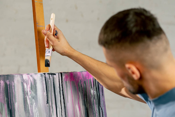 fechar em um estúdio de arte o artista cria faixas escuras na tela com uma escova grande - Foto, Imagem