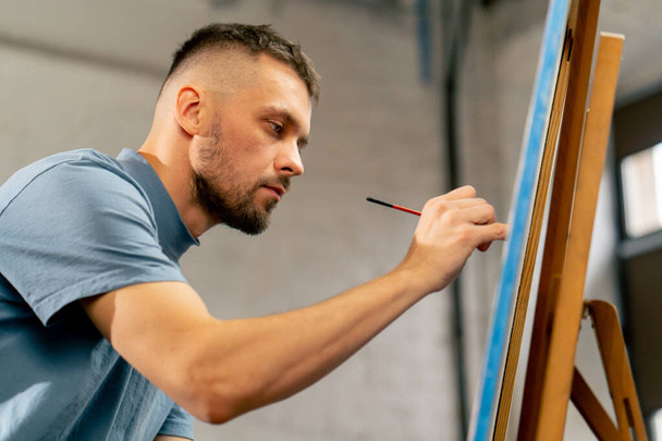 nello studio d'arte di un artista che dipinge vicino a un dipinto con un pennello rosso - Foto, immagini