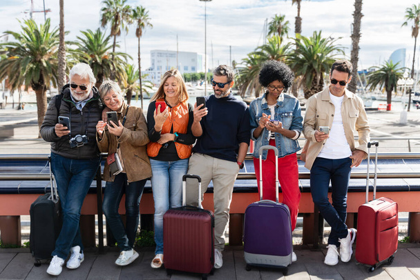 Grupo de personas casuales de diferentes edades usando teléfonos celulares durante un viaje - Foto, Imagen