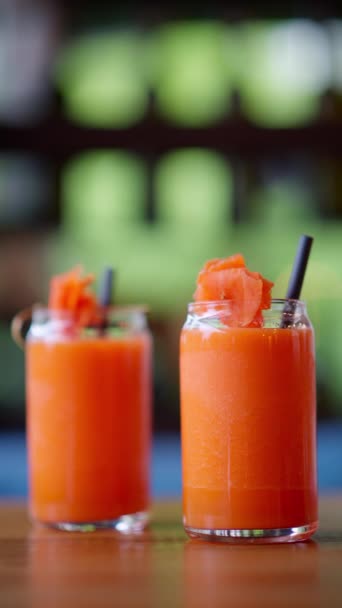 Due bicchieri di succo di carota, sul tavolo di un ristorante. Verticale - Filmati, video