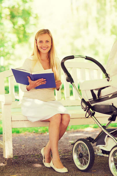 happy mother with book and stroller in park - Фото, зображення