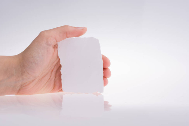 Ruka držící roztržený kus papíru na bílém pozadí - Fotografie, Obrázek