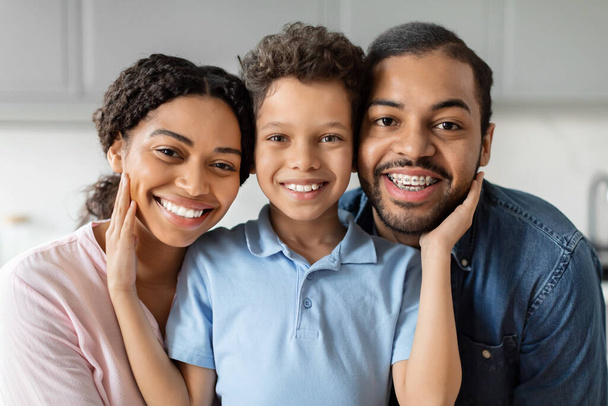 Крупный план счастливой чёрной семьи с сияющими улыбками на кухне, олицетворяющей крепкую связь и любовь - Фото, изображение