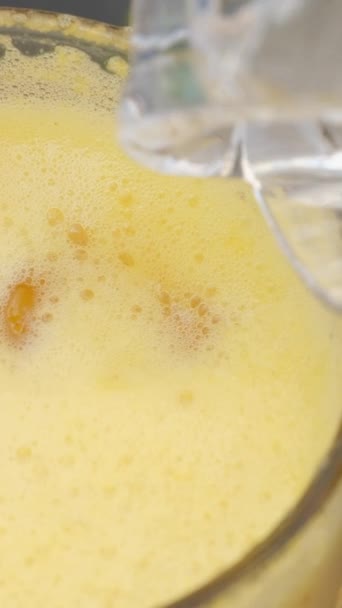 Fruchtsaft mit Eiswürfeln im Glas Closeup. Frisches Orangengetränk mit natürlichen flüssigen Vitaminen im Glas für gesunde Ernährung. Gute moderne Speisekarte mit gekühlten Getränken  - Filmmaterial, Video
