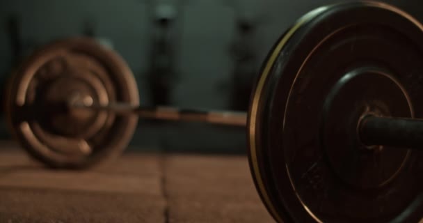Tiro de mano en tiempo real de barra con placas pesadas de hierro fundido con abrazaderas colocadas en el suelo del gimnasio contra el equipo - Metraje, vídeo