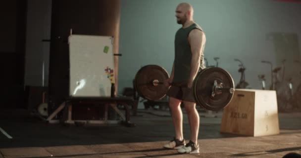 Спортивный культурист-мужчина в спортивной одежде, поднимающий штангу, и юная спортсменка, занимающаяся подтягиванием во время интенсивных тренировок в спортзале - Кадры, видео