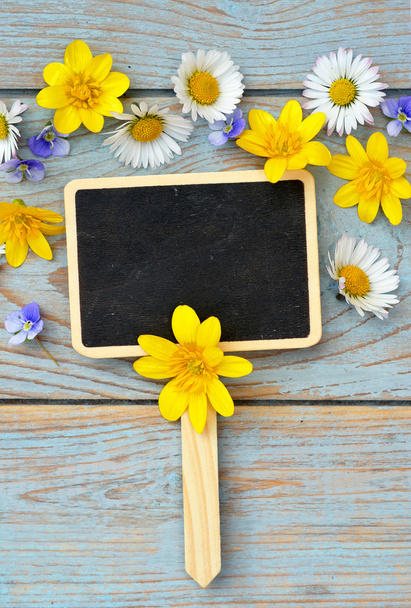 Panneau de craie noir vide sur un vieux bois gris bleu noué usagé avec marguerites et buttercups printemps et été pour une atmosphère sereine fleurs
 - Photo, image