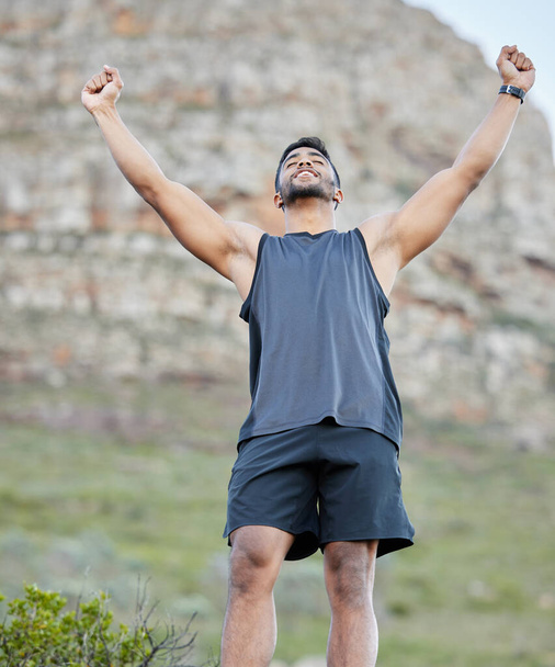 Winner, man and runner in nature with hands up, sports achievement or success in park for fitness. Air, eye closed and athlete in celebration for victory, goals or race in outdoor training or workout. - Photo, Image