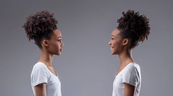 Juicio y alegría chocan en un diálogo visual entre dos expresiones de la misma mujer negra - Foto, Imagen