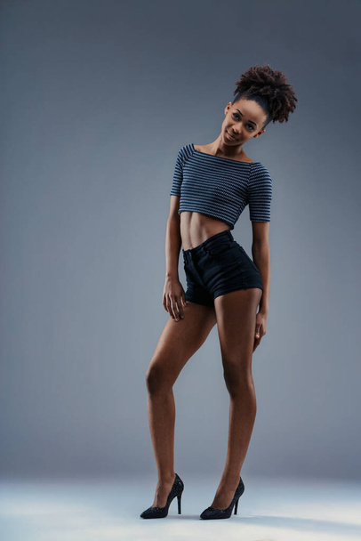 Trendige junge Frau modelliert ein bauchfreies Top und Shorts mit glitzernden Absätzen - Foto, Bild