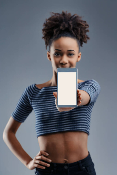 Podekscytowana młoda kobieta pokazuje smartfona, jej wyraz twarzy odzwierciedla obietnicę nowoczesnej komunikacji - Zdjęcie, obraz