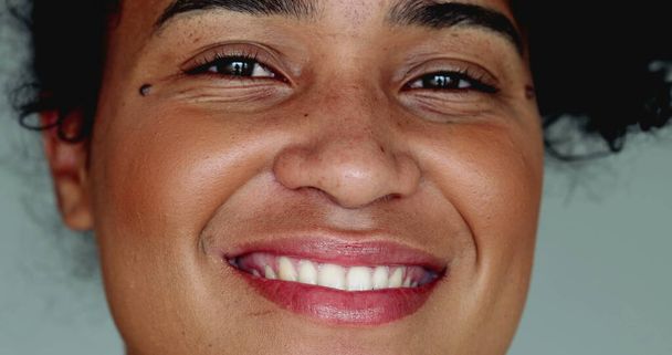 jeden szczęśliwy młody czarny brazylijski kobieta z Afryki pochodzenia uśmiecha się do kamery w mocno makro zbliżenie twarzy szczegół uśmiech z przyjazny zachowanie - Zdjęcie, obraz