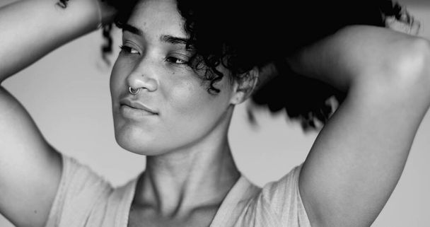 アフリカ系の若いブラジル人黒人ラテン系の女性は,モノクロマティック,黒,白のカーリーヘアスタイルで演奏します. 女性の肖像 20代の人が髪のスタイルを調整する準備ができている - 写真・画像