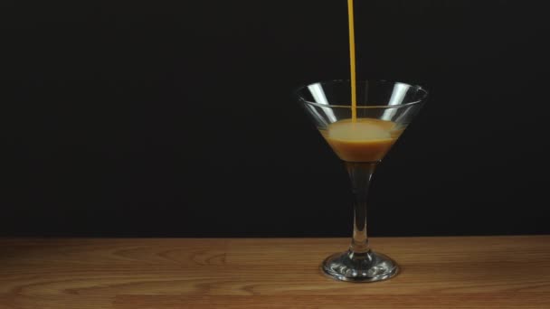 Liqueur is poured into a martini glass. Cinnamon-colored alcoholic drink. Alcoholism, drunkenness in a bar. The sweet drink has a low alcohol content - Footage, Video