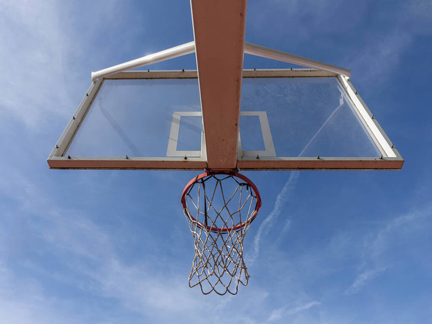 Μπάσκετ στεφάνι με δίχτυ από κάτω σε ένα υπαίθριο γήπεδο με φόντο τον ουρανό - Φωτογραφία, εικόνα