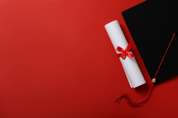 Chapéu de graduação com diploma em fundo vermelho. - Foto, Imagem