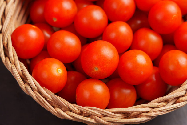 Зрізати помідори вишні на кухонному столі в мисці з ротанга крупним планом. Здорові органічні овочі. Вид зверху - Фото, зображення