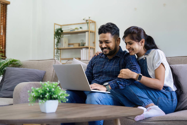 Щаслива індійська пара Використовуючи ноутбук Перегляд Інтернету Разом на дивані вдома. - Фото, зображення