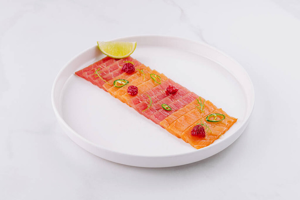 Mésszel és gyógynövényekkel díszített lazacos sashimi elegáns bemutatása fehér tányéron - Fotó, kép