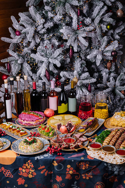 Cadre somptueux de table de vacances avec une variété de plats devant un arbre de Noël magnifiquement décoré - Photo, image