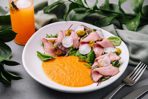 Lebendiges Gericht aus Roastbeef-Salat mit buntem Dressing, serviert mit einem erfrischenden Orangensaft - Foto, Bild